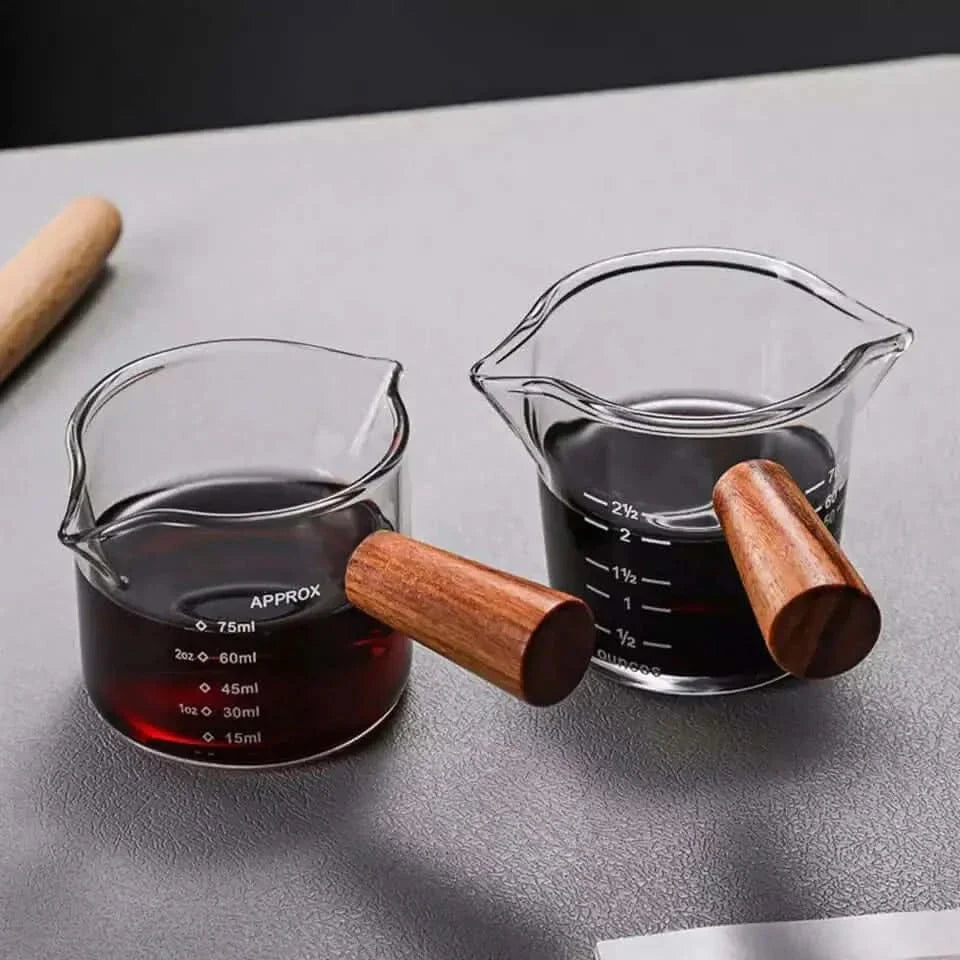 Two glass measuring cups with wooden handles.