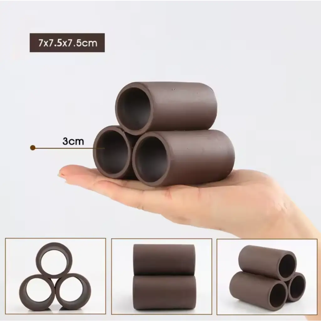 Three dark brown ceramic tubes stacked on a hand.