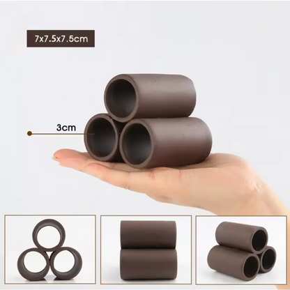 Three dark brown ceramic tubes stacked on a hand.